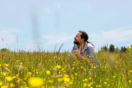a handsome bearded man sitting in a wildflower meadowの写真素材
