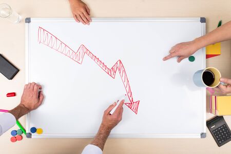 negative balance on whiteboard, overhead view with multiple hands