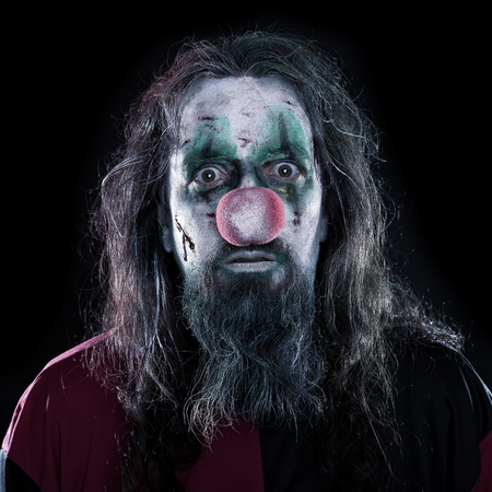 Portrait of a creepy and bloody clown in front of black background, concept Horror or Halloween