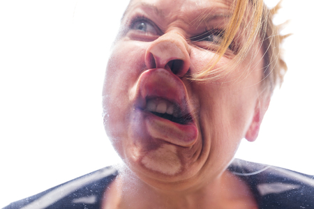 woman is running against a pane and makes a funny grimaceの写真素材