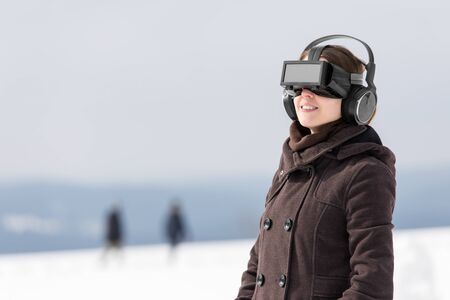 woman enjoys her virtual reality glasses in a winter landscape
