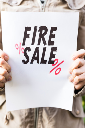 Woman is holding a paper, with the sentence fire saleの写真素材