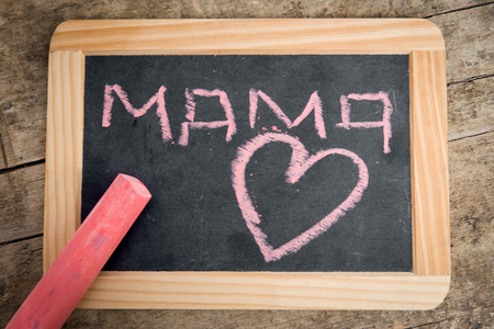 Old blackboard with Word Mama and a Heart, written with pink chalk, vintage wooden tableの写真素材