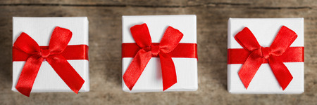 Little gifts boxes with red ribbons on wooden table, panorama and flat lay