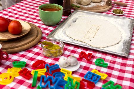 cut out letters, dough on a griddle, red white tableclothの写真素材