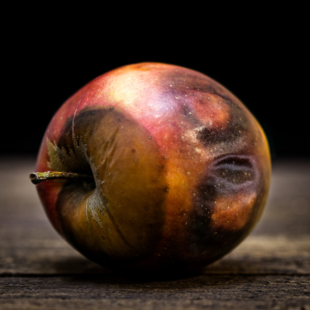 rotten apple on a wooden table, looks like wearing a maskの写真素材