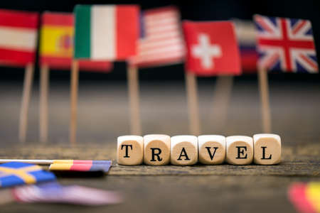 wooden squares with the inscription travel, different country flagsの写真素材