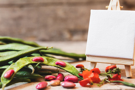 garden beans on a wooden table with blossom and empty board