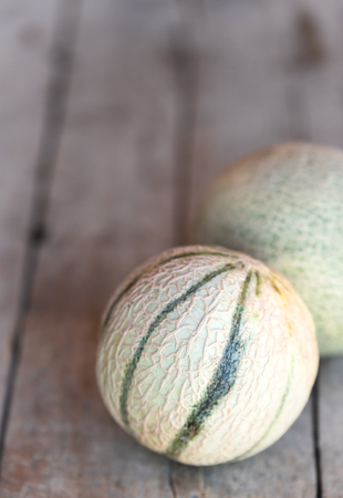 two cantaloupe melons on a wooden table, copyspace in the backgroundの写真素材