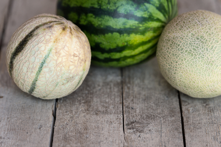 three different melons on a wooden tableの写真素材