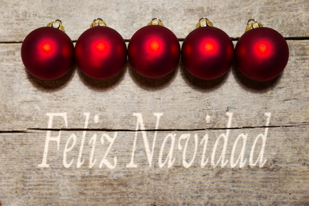 Red christmas balls on wooden table, spanish text feliz navidad, which means merry christmasの写真素材