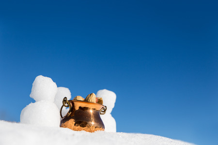 little snowmen figures and a bowl with peanuts in the snow, blue sky in the backgroundの写真素材