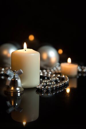 Festive christmas decoration in white, lightning candles, black backgound and christmas ballsの写真素材