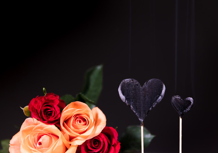 Burnt hearts with rose bouquet in front of black backgroundの写真素材
