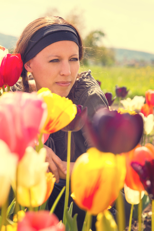 young attractive woman behind colorful tulips in the natureの写真素材