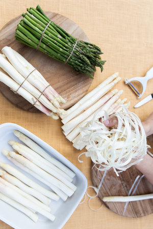 white and green asparagus on a table, woman is peeling the asparagus, topviewの写真素材