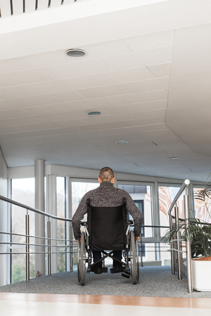 man sitting in a wheelchair, backview in a hospitalの写真素材