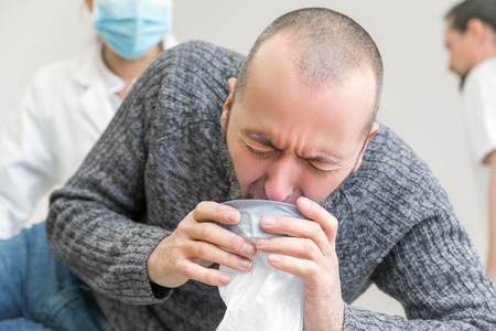 male patient in clinic is vomiting in a plastic bagの写真素材