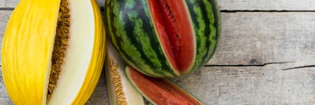 panorama of watermelon and canary melon on a wooden tableの写真素材