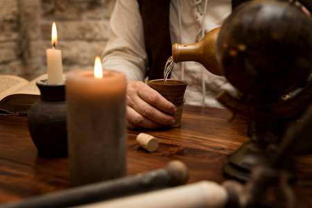 Medievally decorated table, man pour out a drinkの写真素材