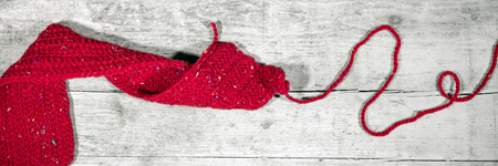 red crocheted scarf on wooden table, handiwork, Header and Bannerの写真素材