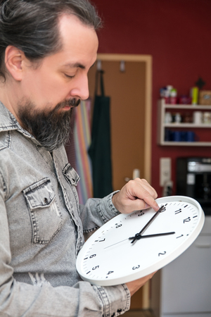 a man changes the time on a clock, daylight savings or change return to standard time