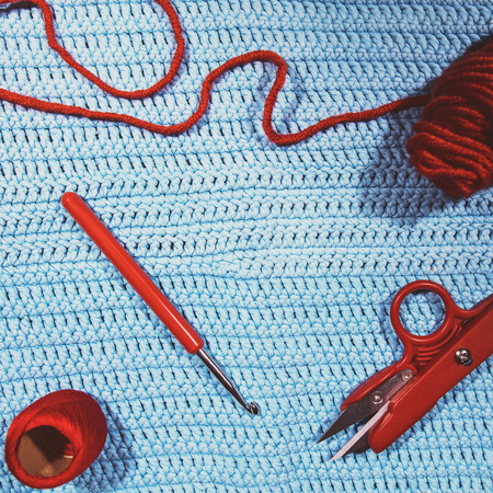 crochet hook, scissors, yarn and woolen ball on crocheted cloth, handiworkの写真素材