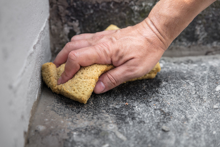 man is cleaning fresh mortar joints with a sponge