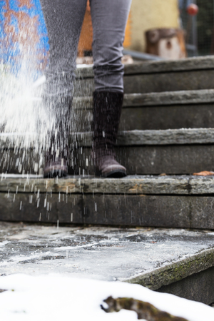 woman is salting iced stairs in the winterの写真素材
