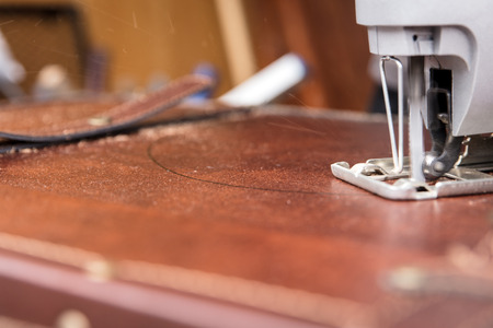 Man is cutting a cutout with a jigsaw into a chestの写真素材