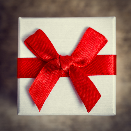 Closeup from a little gift box with red ribbon, flat lay, vintage filtered