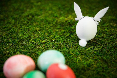 Background, easter bunny figures and colorful dyed easter eggs on green mossの写真素材
