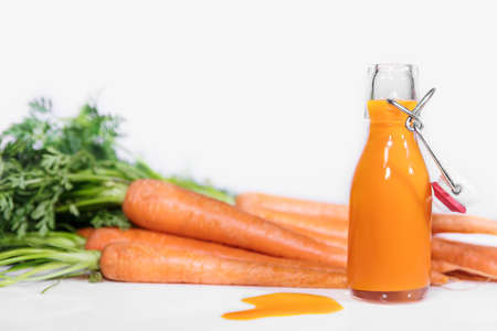 fresh carrots with bottle of healthy juice in front of a white backgroundの写真素材