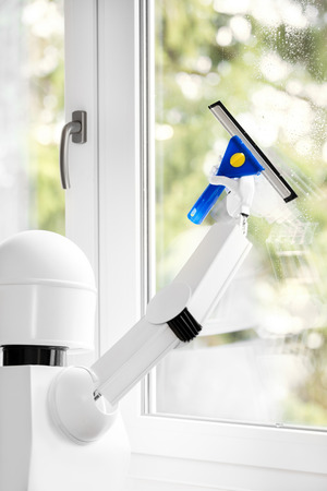 a autonomous robot is washing a window with a tool, using his robot hand for the routine jobの写真素材