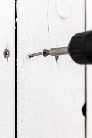 A chipboard screw is screwed into a board, wooden board is fixed with screw by a cordless screwdriverの写真素材
