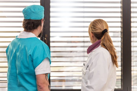 two doctors or nurses in front of a window are looking outの写真素材