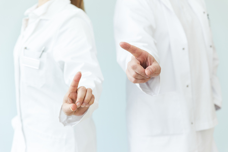 female and male doctor are using their fingers and holding them in front of their bodys. lot of copyspace concept touchscreen or interactive medicineの写真素材