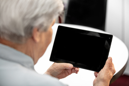 Modern grandma looking at the desk from a tablet with copyspace, elderly women and computer technologyの写真素材