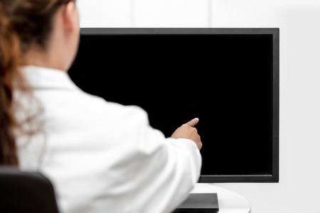 Backview, female doctor or lab assistant is pointing on a black desk or monitor with copyspaceの写真素材