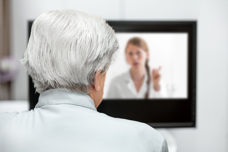 In-home care for an elderly patient with telemedicine or telehealth, virtual live chat on the monitorの写真素材