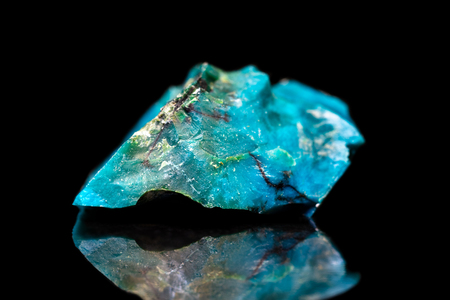 Raw gemstone in front of black, blue Chrysocolla mineral stone with reflectionの写真素材