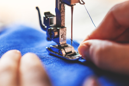 closeup of a woman, trying to thread a needle of a sewing machine