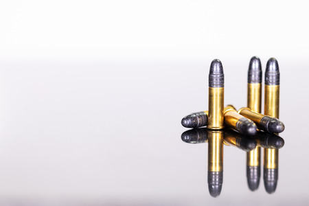 group of ammunition on a table with reflections, white background