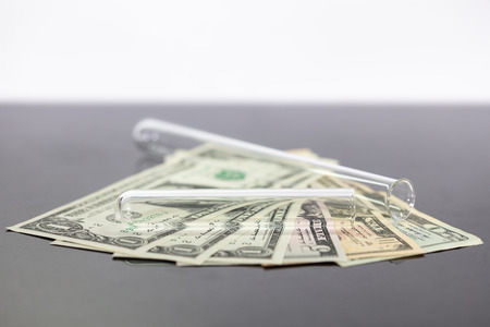 Several dollar notes with test tubes, concepts such as expensive medicine, statutory or private health insurance or high tuitionの写真素材