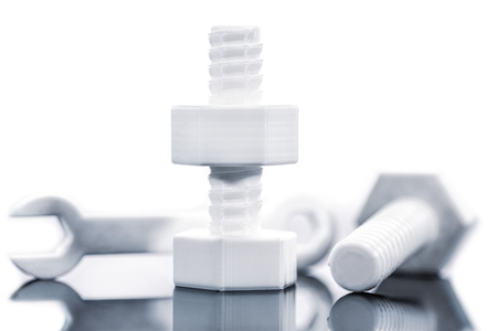 Hexagon screw and wrench of filament printed with reflection in front of white backgroundの写真素材