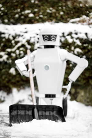 service robot is shovelling snow in the winter, portrait of the autonomous robot while standing in the snowの写真素材