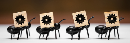Four ants carry wooden blocks with the symbol of a cogwheelの写真素材