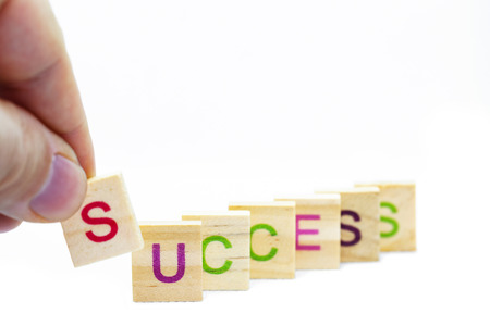 Many letters on wooden blocks yield the word success, isolated on whiteの写真素材