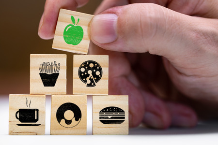 Concept healthy food, wooden blocks with different symbols of fast food, above an apple in green