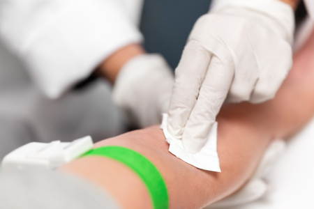 Preparation for blood sampling, patient with a tourniquet band and swab on the arm, closeup